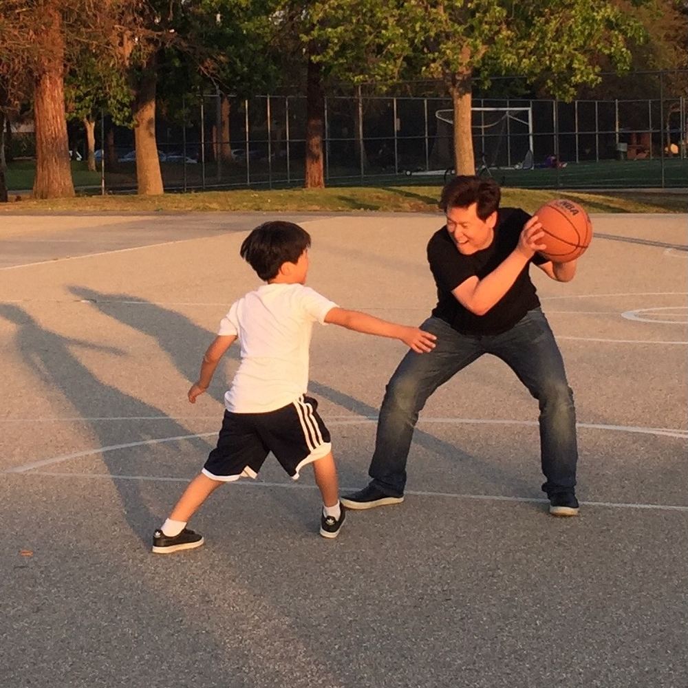 Young Ethan in a defensive stance guarding a taller player holding the ball