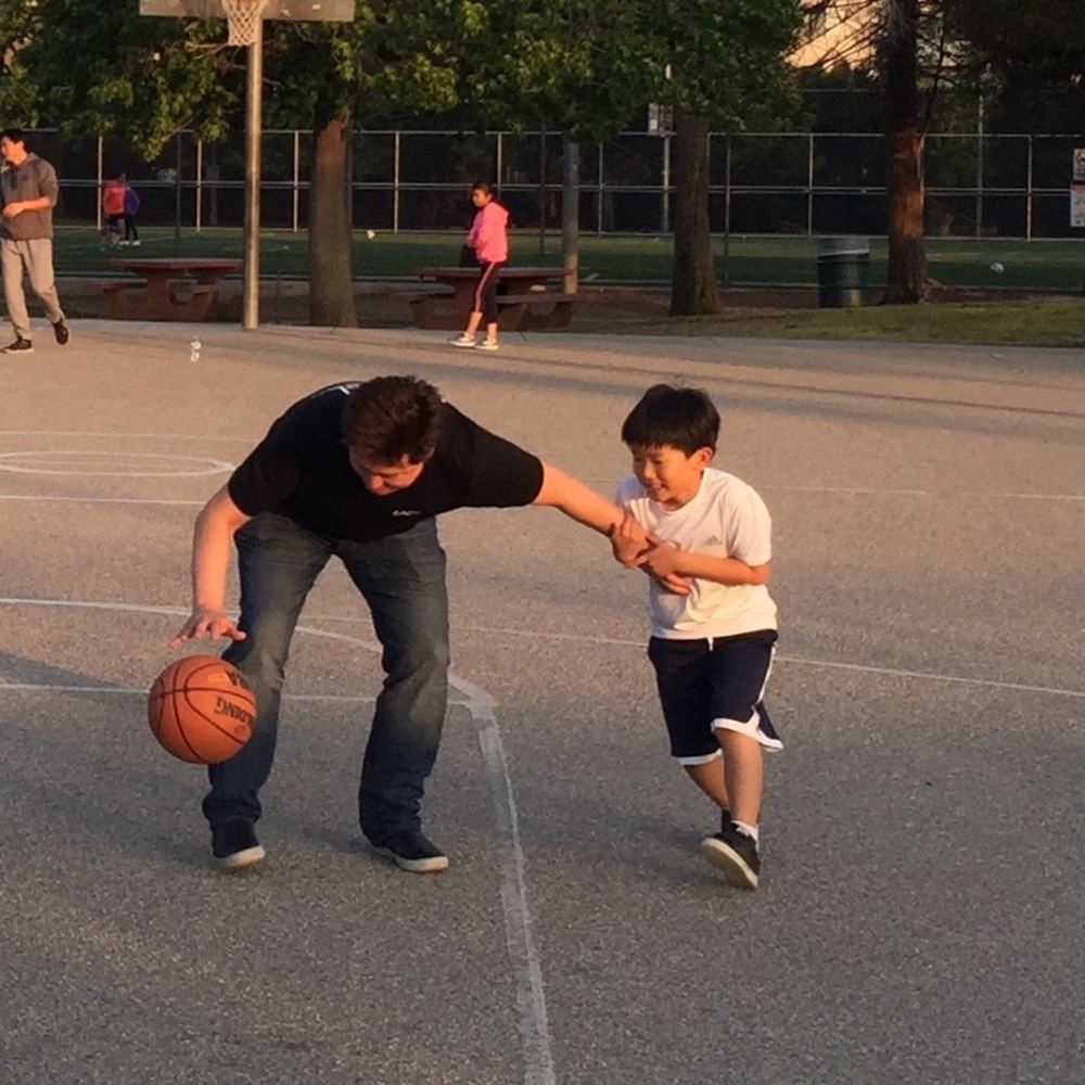 Young Ethan reaching for the ball as a taller player dribbles past him